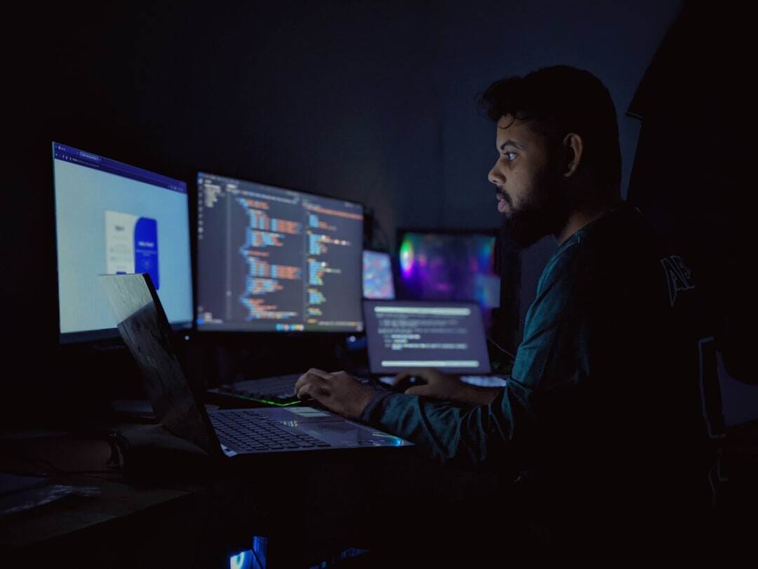 Software code on multiple monitors in a dark developer workspace